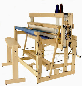 The Louët Octado 8-shaft Floor Loom without Dobby Control Head by Louët Inc. is a wooden handloom designed for weaving textiles. It features multiple pedals, levers, and mechanisms for thread arrangement and control. Two cones of thread can be positioned on top, and an adjacent bench allows the user to operate the loom efficiently.