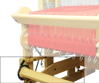 A close-up view shows the Louët Second Warp Beam for the Megado Loom, featuring part of its wooden frame with red threads. Metal hooks guide the threads while gears at the bottom left allow for tension adjustment. The partially visible wooden frame and mechanical components highlight Louët Inc.'s intricate setup.