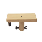 The Louët Footrest from Louët Inc. is a beautifully designed wooden rectangular block connected to a cylindrical post. It features a versatile clamp mechanism with a butterfly screw on one side and a round knob on the other, allowing for easy adjustments. The footrest, which complements the loom's wood finish, seems to be part of an ergonomic mount or bracket system. It is showcased against a plain white background.