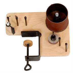 The Louët Warp Tension Regulator by Louët Inc. is a wooden tool holder equipped with an attached metal clamp at the bottom. Multiple rods of varying sizes are positioned upright on the holder, and a cylindrical sanding drum is mounted on the right side. This setup, which includes an adjustable tension capability, seems ideal for sanding or woodworking tasks.