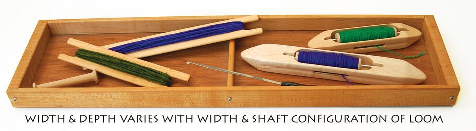 A hardwood tool tray, designed by Harrisville Designs for their 36" Harrisville 4 or 8 Shaft Loom, holds weaving tools including two shuttles wound with blue and green threads, along with several heddles also wrapped in green and blue threads. The text below reads: "Width & depth varies with width & shaft configuration of Harrisville Design looms.