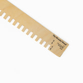 A wooden tool called the "Harrisville Lap Loom Wonder Wand" by Harrisville Designs, perfect for weaving on a Lap Loom, designed with evenly spaced square notches along one edge. The tool features marked measurements and arrows labeled "B" and "A" near the handle.