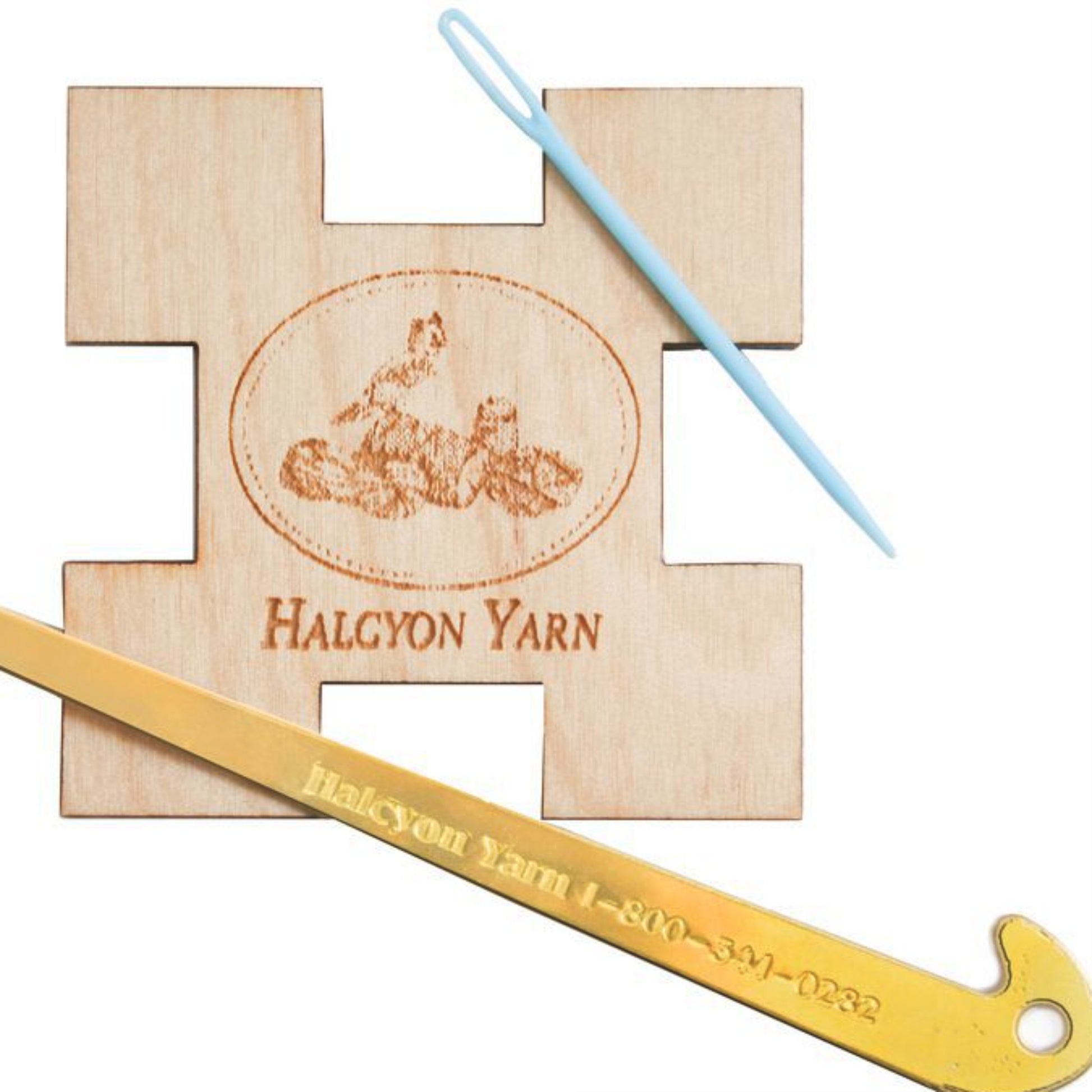 The Halcyon's Brass Threading Hook & Wooden Sett Tool set from Halcyon Yarn includes a charming wooden yarn gauge tool with an engraved sheep logo and "Halcyon Yarn" text, a light blue plastic yarn needle, and a brass threading hook engraved with "Halcyon Yarn 1-800-341-0282," ensuring all your weaving needs are met.