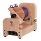 The Ashford E-Spinner 3, an electric spinning wheel by Ashford Handicrafts Limited, boasts a modern design in compact, boxy shape for easy use. This small wooden spinner features a visible spool of purple and blue thread, multiple adjustment knobs, and an on/off switch at the base.