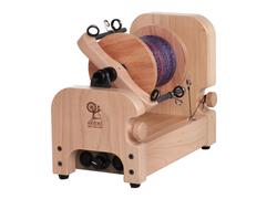 The Ashford E-Spinner 3, an electric spinning wheel by Ashford Handicrafts Limited, boasts a modern design in compact, boxy shape for easy use. This small wooden spinner features a visible spool of purple and blue thread, multiple adjustment knobs, and an on/off switch at the base.