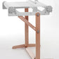 The Ashford Rigid Heddle Table Stand by Ashford Handicrafts Limited is a weaving stand crafted from wood and metal. This stand includes adjustable knobs for controlling height and tension, a sturdy wooden base with two legs for stability, and a metal frame on top with a roller to hold the weaving material. Its minimalistic design also offers an adjustable weaving angle for added convenience.