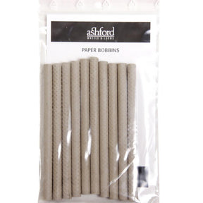 A package of Ashford Paper Bobbins for Boat Shuttles (10/Pack), vertically aligned and enclosed in clear plastic packaging. The label at the top reads "Ashford Handicrafts Limited" and "Paper Bobbins." The textured, cylindrical bobbins are perfect for use with an Ashford Boat Shuttle.