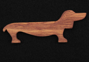 The Dachshund Wiener Dog Weaving Shuttle from Weiner Dog Ranch is a mahogany weaving accessory shaped like a dachshund, showcasing the dog's long body and short legs. Displayed against a plain black background, the visible wood grain adds texture to this handcrafted piece.