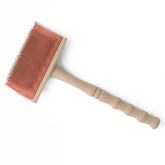 The Ashford Flicker by Ashford Handicrafts Limited features a lathe-turned wooden handle for a comfortable grip, along with a rectangular head containing densely packed metal bristles set in a red cushion. Perfect for cleaning drum carders, it's displayed against a white background.