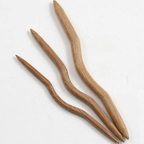 Against a plain, light background, three Bamboo Cable Stitch Holders by Accessories Unlimited are displayed. This elegant set of 3 features slightly curved, smooth-finished holders that showcase the natural grain and texture of the bamboo. The holders are arranged parallel to each other from shortest to longest.