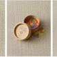 Three images highlight different stages of knitting: the first features Cocoknits' vibrant Colored Ring Stitch Markers, the second shows an open container filled with these essential knitting accessories from Cocoknits, and the third displays a knitted swatch on needles with some Cocoknits nylon coated steel stitch markers in use.