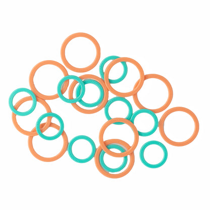 A variety of green and orange plastic ring stitch markers by Bryson Distributing, Inc., featuring both large and small sizes, scattered randomly on a white background.