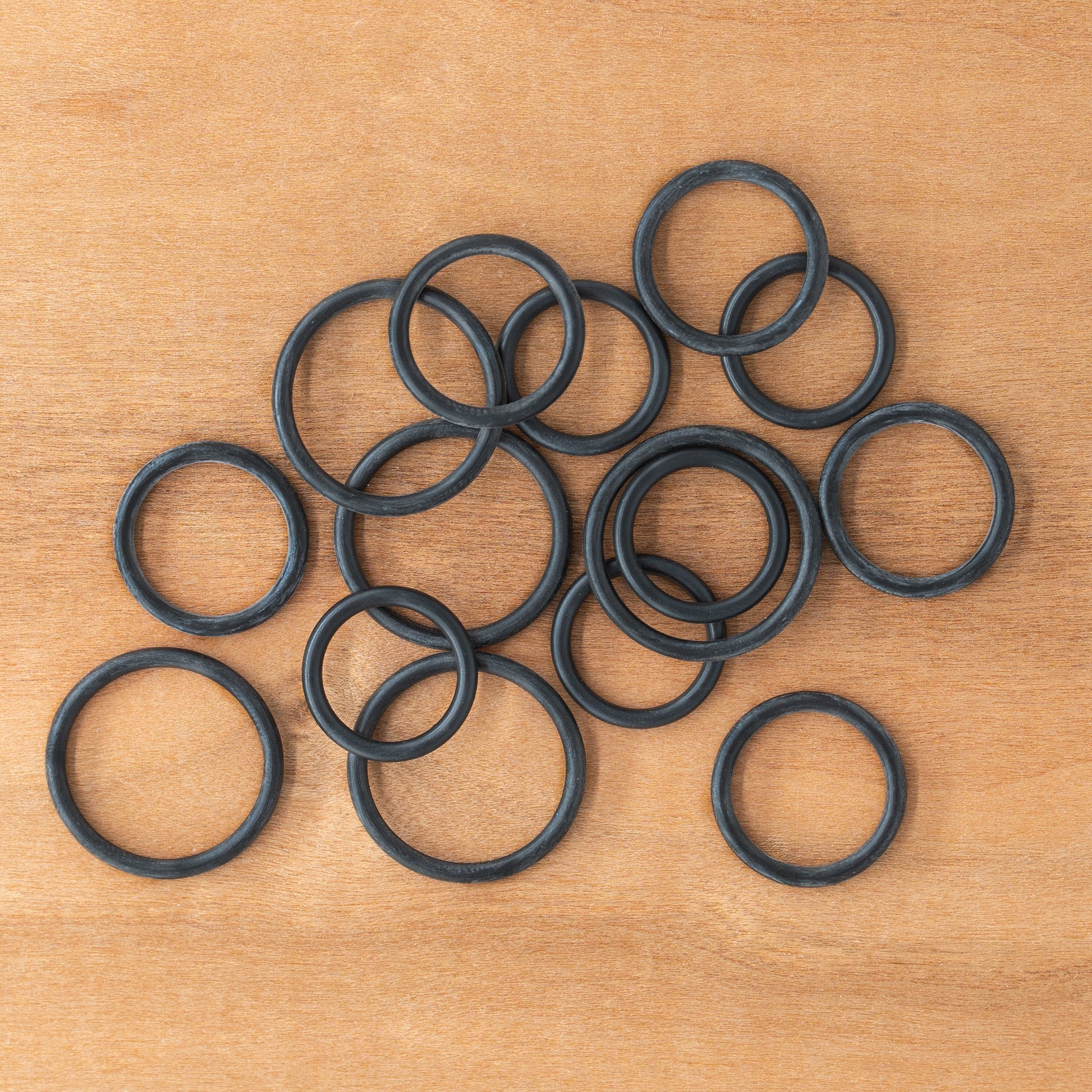 A selection of Bryson Rubber Ring Markers by Bryson Distributing, Inc., resembling small ebony markers, is scattered on a wooden surface.