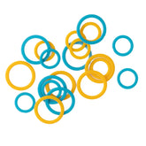 A scattered assortment of Bryson Distributing, Inc.'s Soft Stitch Ring Markers in gentle hues of blue and yellow, available in varying sizes, displayed on a white background.