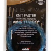 A package of blue Addi-Click Cord Pack knitting needles by Skacel with an attached circular cord in its original packaging. The text on the package reads "Knit Faster with the Amazing Addi Turbo" and provides product details in English. Icons of animals and knitting notions are visible in the background, making it an ideal addition to any Booster Cord Pack collection.