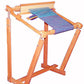 A wooden tapestry weaving frame, akin to the Beka Rigid Heddle Floor Stand by Beka, features a piece of colorful fabric in progress. The frame is adjustable with a tilted upper section that holds the fabric tightly, showcasing a partially finished woven piece. The sturdy base provides solid support similar to loom stands.