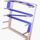 The Beka Warping Board by Beka is a wall-mounted rack with multiple tiers designed to hold and organize rolled-up yoga mats. The frame is white, the tiers feature blue straps to secure the mats in place, and it's easy to assemble. It offers an economical solution for storing your yoga essentials while keeping them tidy.