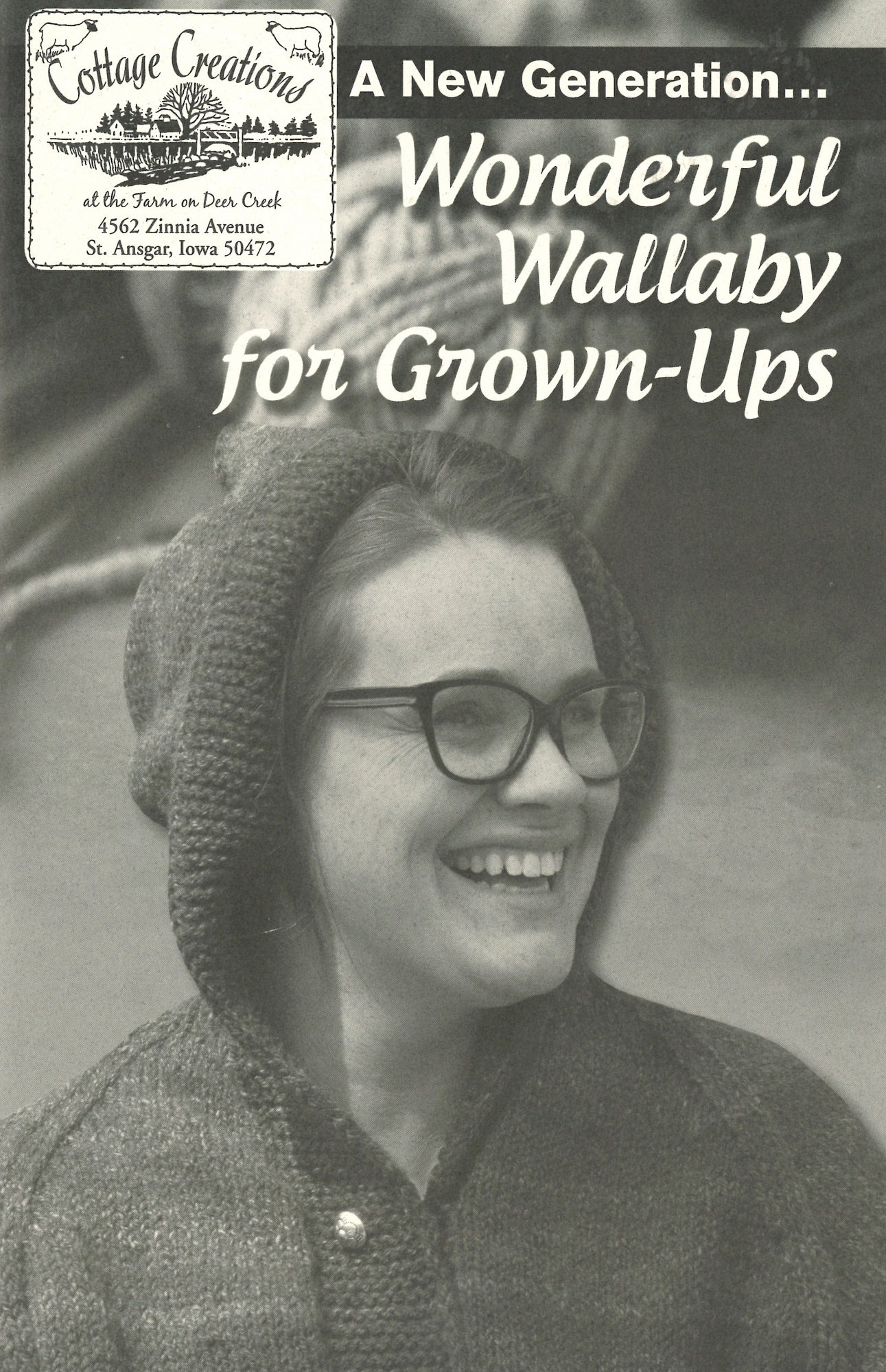 Black-and-white photo of a smiling woman wearing glasses, a hooded sweater with a hand-warming pocket, and looking to her right. The image is overlaid with text: "A New Generation... Wonderful Wallaby For Grown-Ups." Small upper-left logo: Cottage Creations, St. Ansgar, Iowa.