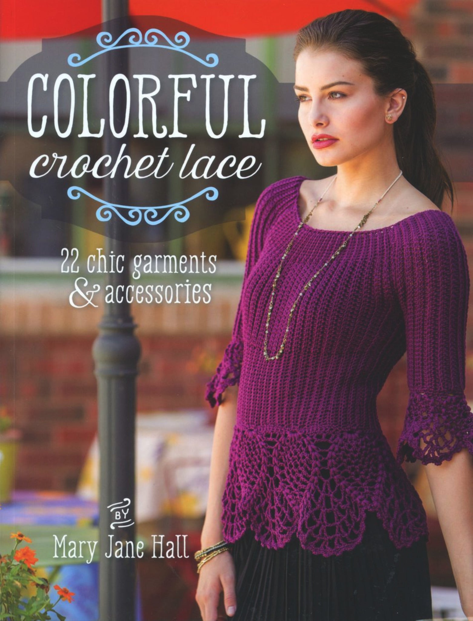 Book cover of "Colorful Crochet Lace - 22 chic garments & accessories" by Mary Jane Hall, published by Ingram Content, showcasing a woman in a purple crochet top with lace details. The cover text highlights "22 chic garments and accessories, including stylish dresses and chic shrugs," surrounded by an elegant decorative design.