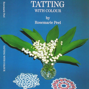 A blue book cover titled "Tatting With Colour" by Handy Hands features a crystal vase with green leaves and white flowers. Below the vase are two exquisite tatting patterns in multiple colors, one blue and white, the other red and white.