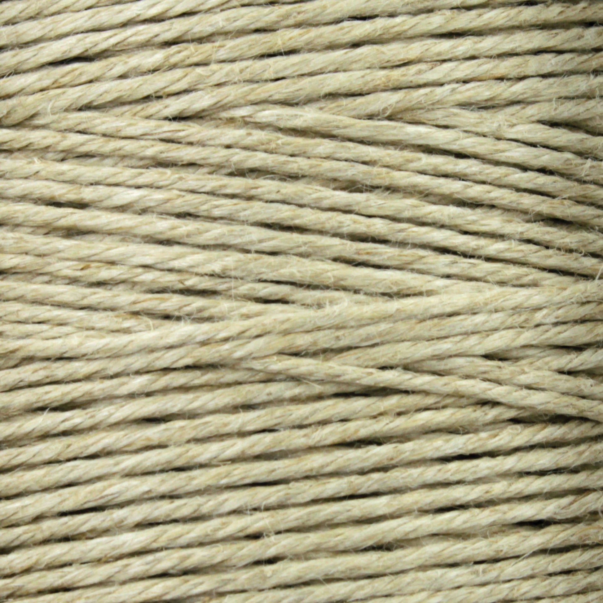 Close-up shot of a spool of Stuart C. Hurlbert & Co.'s Soft Finish Linen Warps in light beige. The fibers are tightly wound, and the texture is clearly visible, showing a slightly rough surface characteristic of natural fiber linen warps used in tapestry weaving.