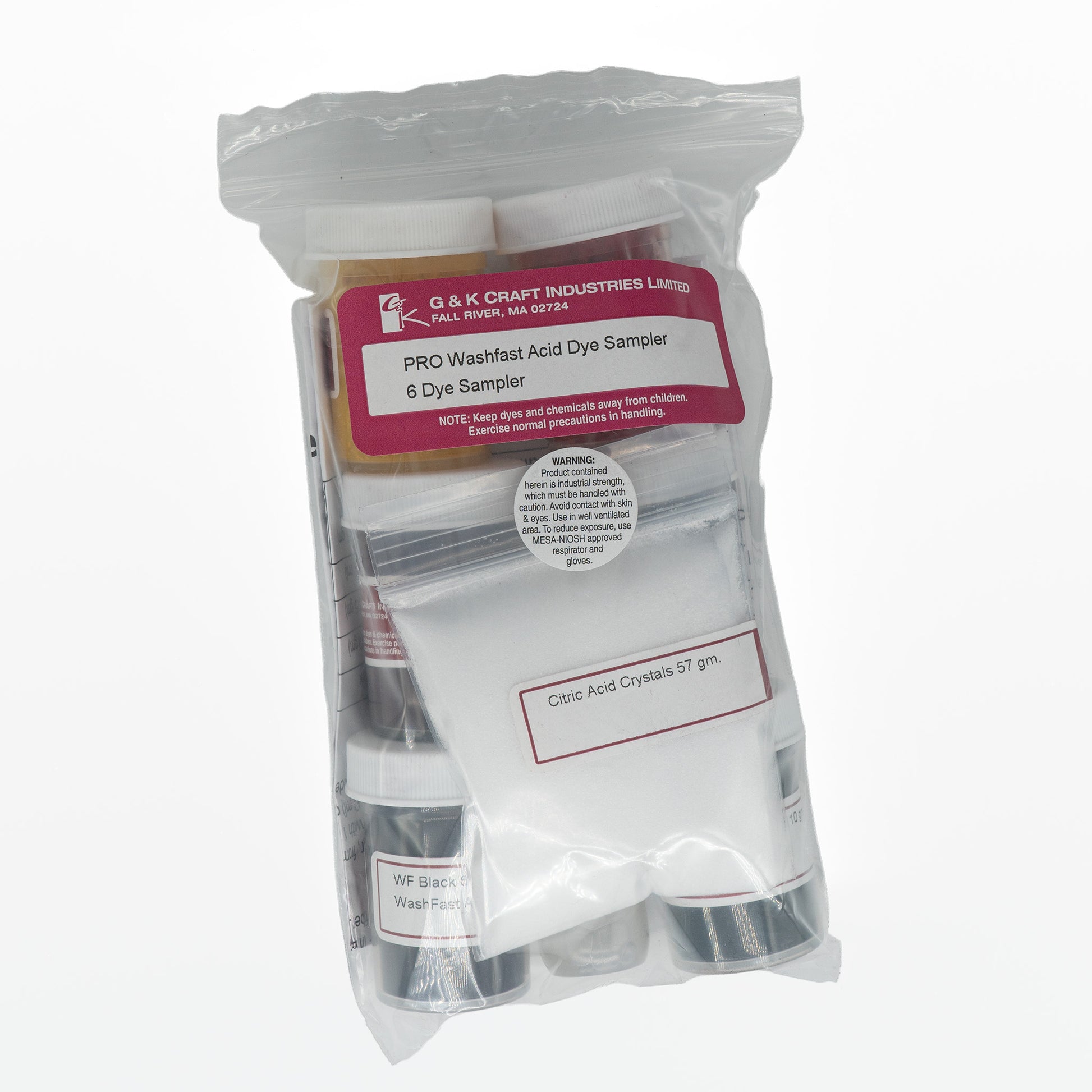 A clear plastic bag contains various labeled containers and packets from G & K Craft. The main label reads "Wash Fast Acid Dye 6-Color Sampler." Items visibly include citric acid crystals, dye containers, and complete instructions, all secured in clear packaging.