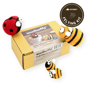 A Woolbuddy Needle Felting Kit features a closed box with the product name and includes wool roving. Three felted figures—two bees and one ladybug—are arranged around and on the box. The Woolbuddy logo with "Felting Kit" is displayed in the top-right corner.