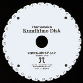 A round white Kumihimo disk labeled "BraidersHand Kumihimo Disk" features evenly spaced numbered slots from 1 to 32 around the outer edge. Japanese text and two icons of braiding tools are printed in the center. Perfect for creating braids, this portable project tool, marketed under the Braiders Hand/Saunders brand, is essential for crafting kumihimo cords.