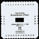 A white square BraidersHand Kumihimo Plate by Braiders Hand/Saunders, designed by Makiko Tada. Perfect for portable projects, it features numbers 1 to 12 around the edges and columns labeled A, B, C, D. There are notches around the edges and a hole in the center for creating braids. Text is in Japanese and English.