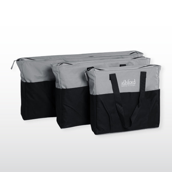 Three Ashford Knitters Loom Bags from Ashford Handicrafts Limited in black and gray are arranged in a row. Each bag, rectangular in shape and equipped with a handle for carrying, is set against a plain, light background.