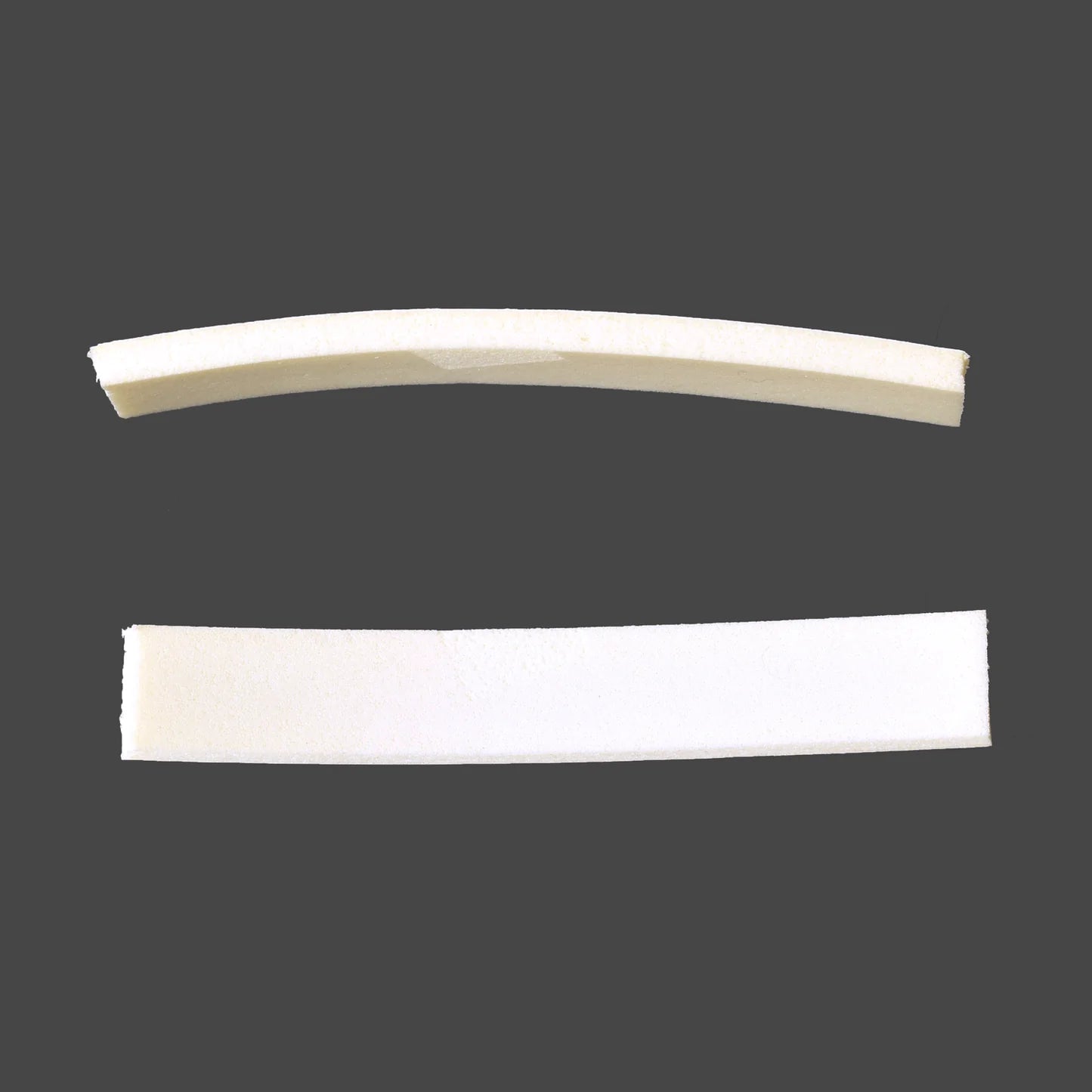 Two white foam strips on a gray background. The top strip, reminiscent of the curves found in 4 shaft looms, is shorter and has a slight curve, while the bottom strip is longer and straight. Both strips are part of Schacht Spindle Co.'s Foam Tape for under shafts (5 Inch).