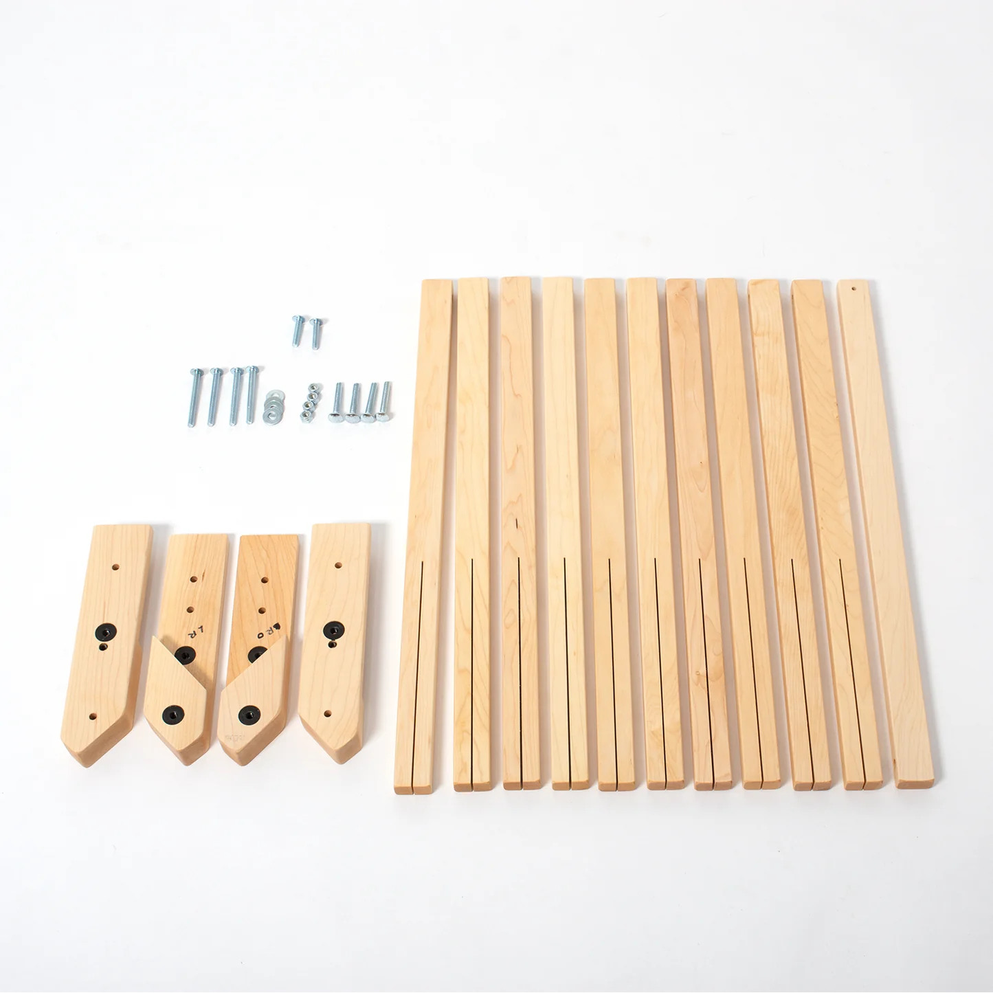 A disassembled Schacht Wolf Loom Height Extender Kit by Schacht Spindle Co. set against a white background. The image shows various wooden components including legs and support pieces, height extenders, as well as screws and bolts laid out neatly.