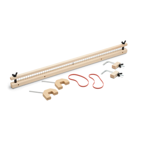 The Schacht Raddle for Wolf Looms by Schacht Spindle Co. includes a rectangular frame with evenly spaced pegs, three U-shaped hooks, a long red string, two metal hooks with wooden bases, and several wooden pieces for assembly, all beautifully arranged on a white surface.