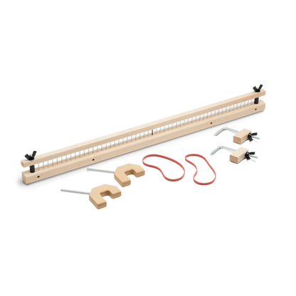 The Schacht Raddle for Wolf Looms by Schacht Spindle Co. includes a rectangular frame with evenly spaced pegs, three U-shaped hooks, a long red string, two metal hooks with wooden bases, and several wooden pieces for assembly, all beautifully arranged on a white surface.