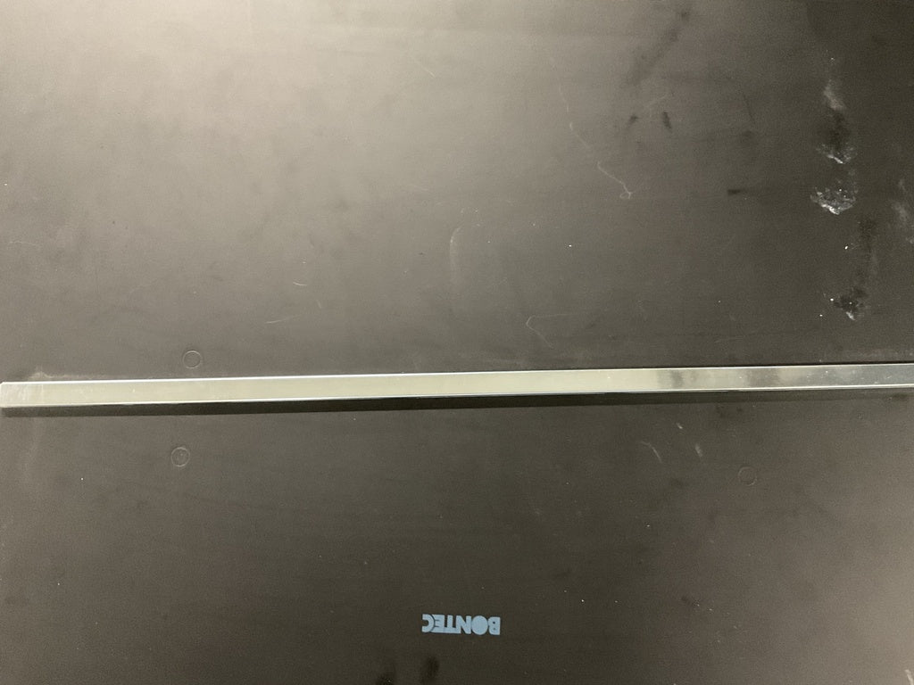 A flat, metallic bar identified as the Louët Metal Shaft Bar W/Kombo/MD by Louët Inc. rests horizontally on a dark grey surface. The word "BONTEC" is inscribed upside down in blue letters near the bottom. The surface shows a few smudges and scratches, resembling an item that might have been misplaced during transport, under subtle and diffused lighting.