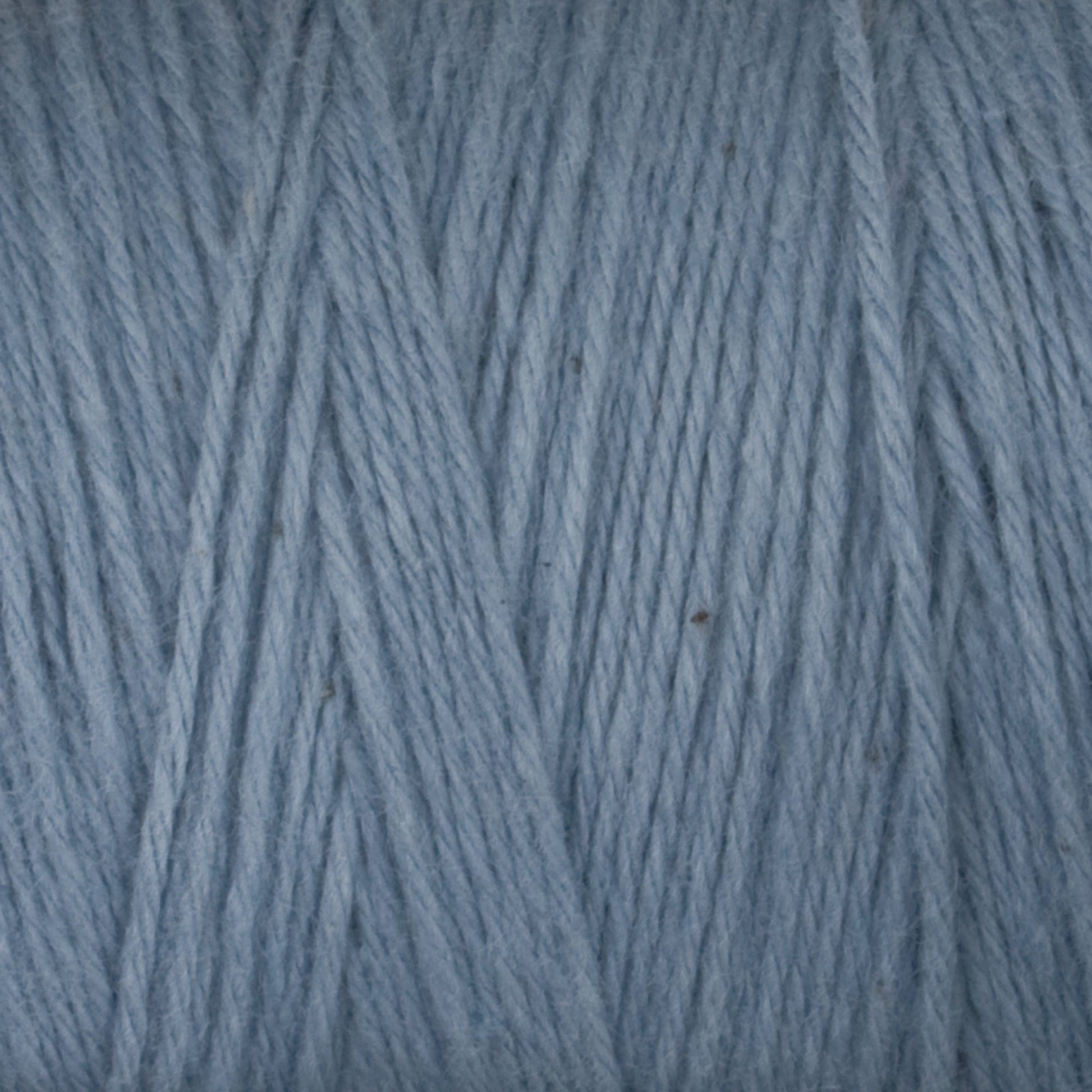 Close-up of light blue, Cotton Carpet Warp 8/4 strands intricately wound together in a crisscross pattern, showcasing a soft, slightly fuzzy texture suitable for colorfast knitting or crocheting projects like cozy rag rugs.