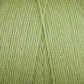 A close-up of the Cotton Carpet Warp 8/4 spool shows tightly wound, light green fibers perfect for rag rugs. The clear texture and diagonal seam create a unique pattern, while its careful crafting ensures durability and vibrant colorfastness.