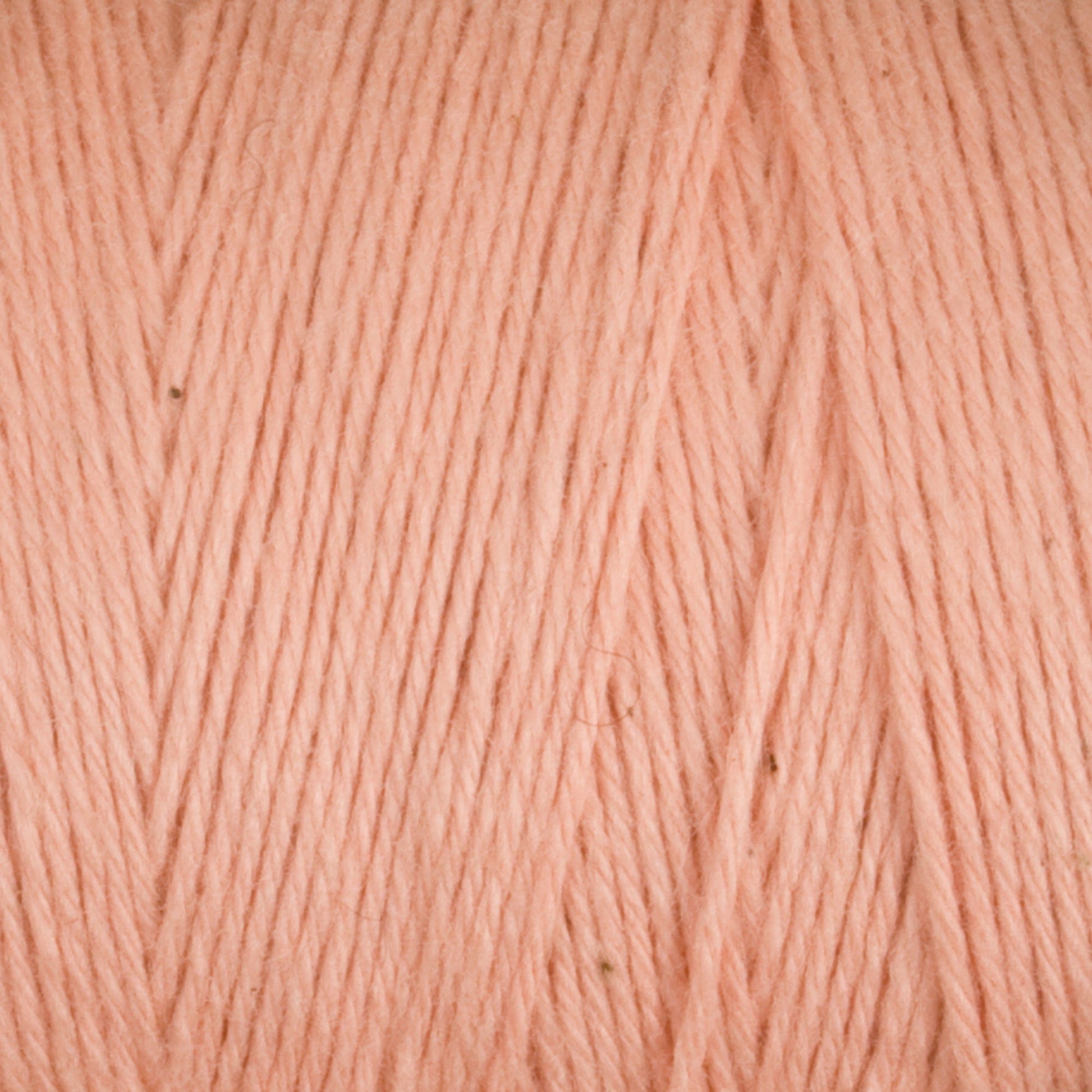 Close-up of soft, pale pink Cotton Carpet Warp 8/4 strands, showcasing texture and fibers. They appear smooth with slight thickness variations, creating a subtle pattern ideal for crafting rag rugs.