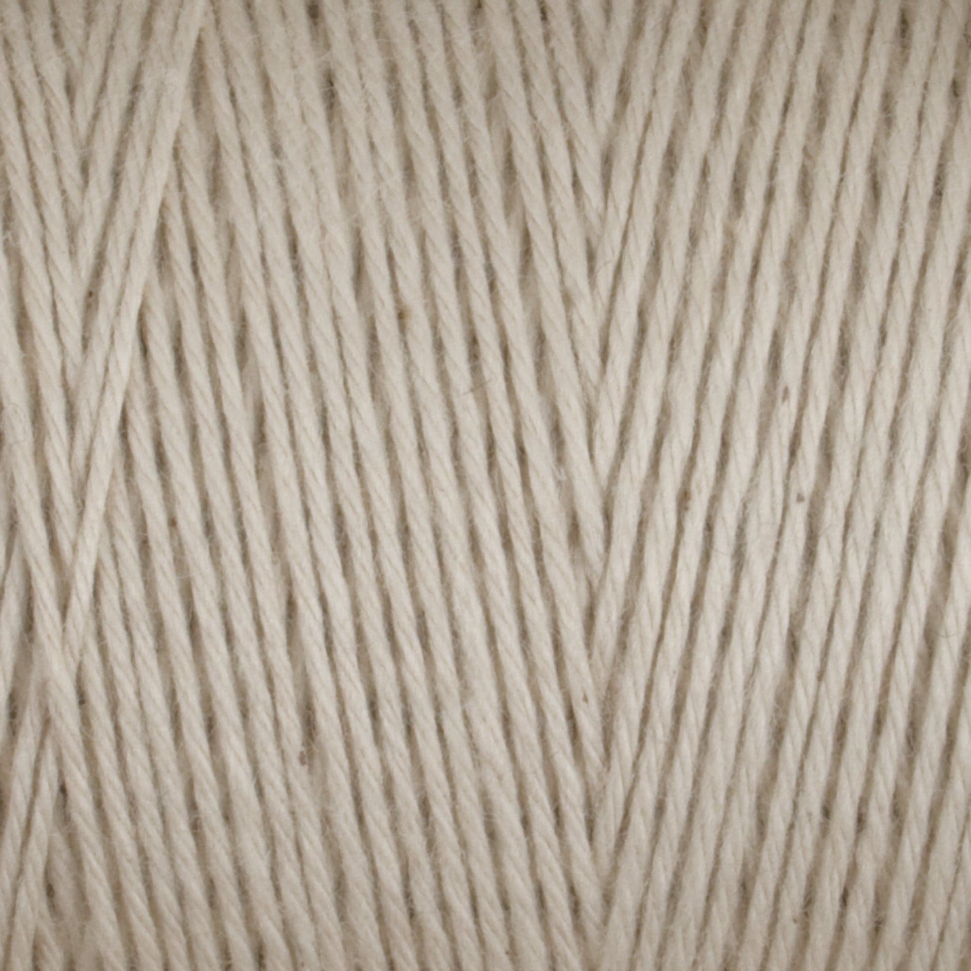 Close-up of a skein of Cotton Carpet Warp 8/4 yarn, ideal for crafting rag rugs. The tightly wound strands showcase the beige texture and thickness, forming neat parallel lines for a uniform, durable surface.