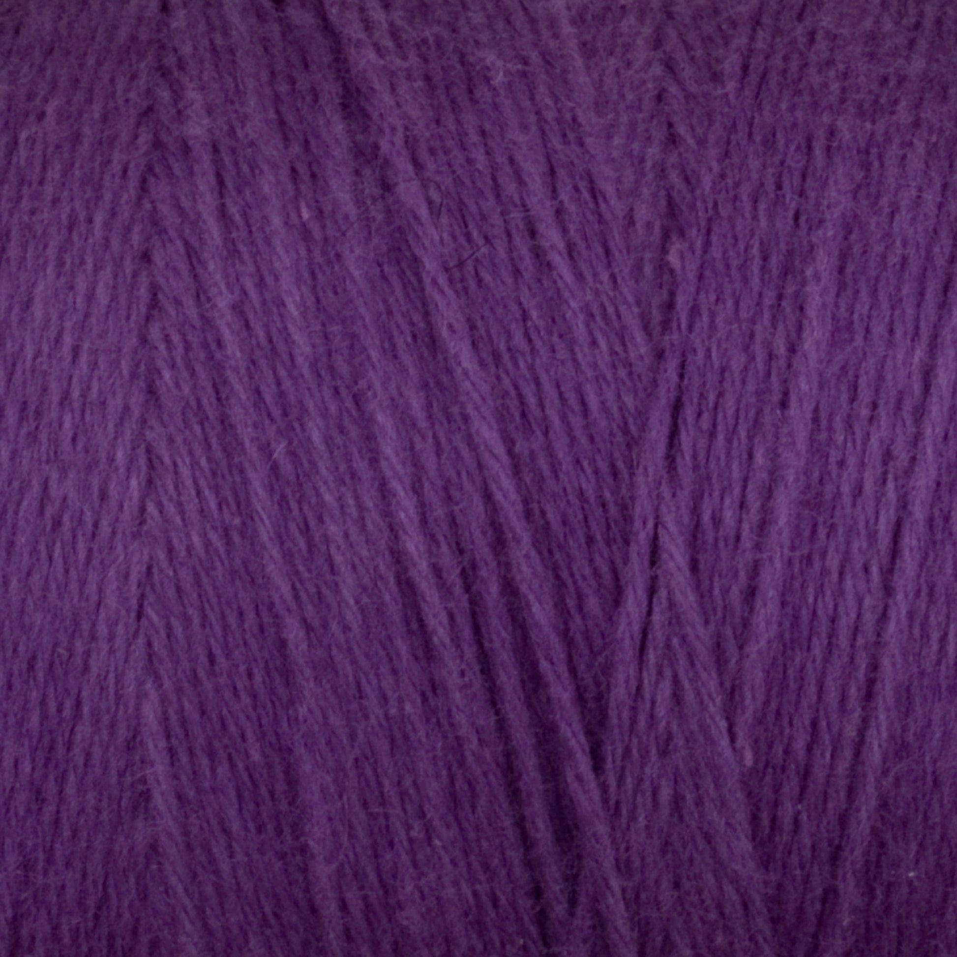 A close-up of the Cotton Carpet Warp 8/4 reveals soft, purple fibers resembling wool, weaving together like rag rugs to form a dense, fuzzy texture.