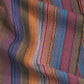 A close-up showcases the vibrant and intricate patterns of the "Best of Handwoven Yarn Series: A Dozen Projects in 10/2 Pearl Cotton (Printed Version)" by Long Thread Media. The fabric features rich hues of red, orange, blue, green, and purple, resembling a finely woven tablecloth with a textured look and slightly undulating surface, suggesting it is laid out loosely.