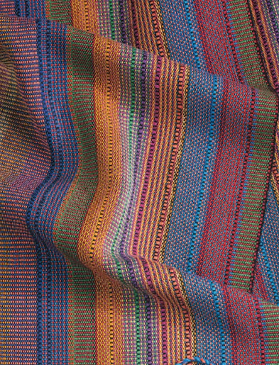 A close-up showcases the vibrant and intricate patterns of the "Best of Handwoven Yarn Series: A Dozen Projects in 10/2 Pearl Cotton (Printed Version)" by Long Thread Media. The fabric features rich hues of red, orange, blue, green, and purple, resembling a finely woven tablecloth with a textured look and slightly undulating surface, suggesting it is laid out loosely.