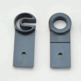 The image shows two Ashford Maiden Bearings from Ashford Handicrafts Limited, both in dark gray plastic on a light gray background. The left bearing features a C-shaped top, while the right one has an O-shaped top. Each item, designed as replacement parts for Ashford Maiden Bearings, has a small hole at the bottom of its rectangular base.