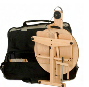 The Louët Victoria Double-Treadle Folding Spinning Wheel, S95 or S96, by Louët Inc., with its contemporary design, is placed in front of an open black carrying case featuring compartments. One compartment contains a spool of yarn. This portable spinning wheel is compact yet efficient for high-speed yarn spinning projects.