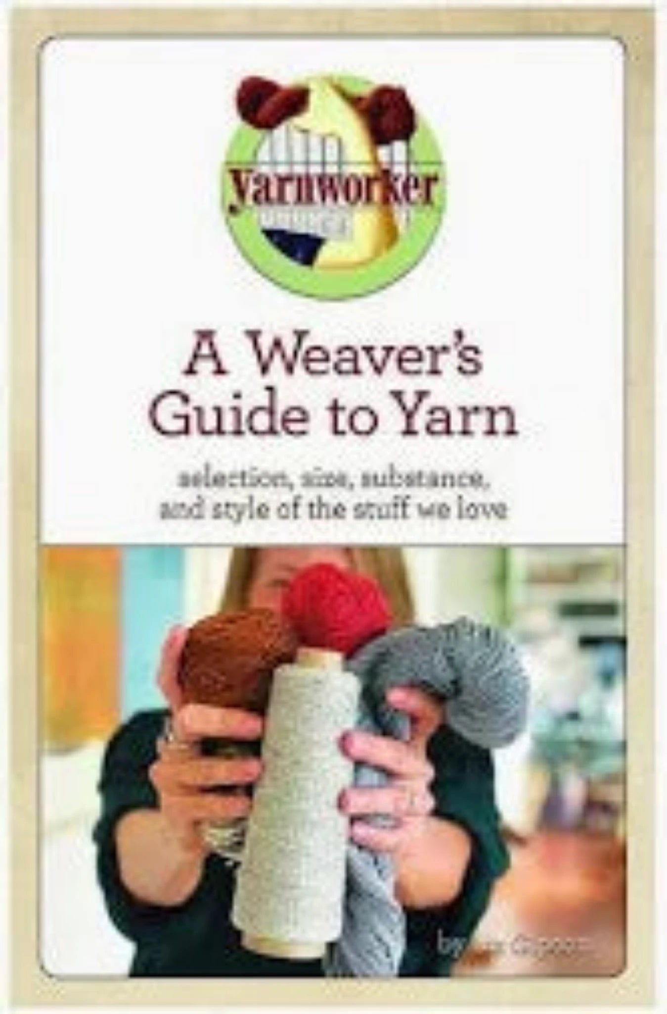 Book cover of "A Weaver's Guide to Yarn" by Liz Gipson, published by Schacht Spindle Co. The cover showcases the title at the top and features a central image of a person holding up three different yarns (grey, cream, and red) against a blurred background. The tagline reads: "selection, size, substance, and style of the stuff we love.