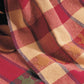 A close-up image of Best of Handwoven Yarn Series: A Dozen Projects in 8/2 Cotton (Printed Version) by Long Thread Media, showcasing a colorful checkered pattern reminiscent of patterned napkins. The fabric displays large squares in shades of red, beige, green, and blue, with intricate detailing and textures visible. The material appears to be draped casually.