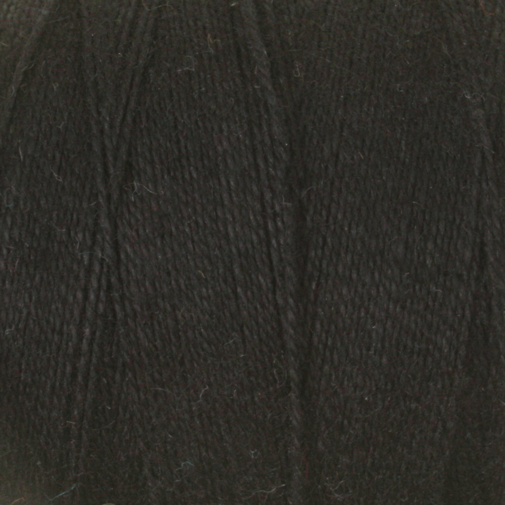 Close-up image of dark, textured 8/2 Cottolin Organic Yarn from Maurice Brassard, tightly wound and showing fibers. The material appears to be suited for knitting, crocheting, or other textile crafts. Made from a cotton linen blend, the deep black color has a slight sheen under the lighting.