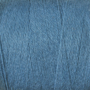 Close-up image of a spool of blue yarn. The yarn, part of the 8/2 Cottolin Organic Yarn | Tube by Maurice Brassard, is tightly wound into neat layers and has a slightly textured surface, showcasing a consistent blue color throughout.