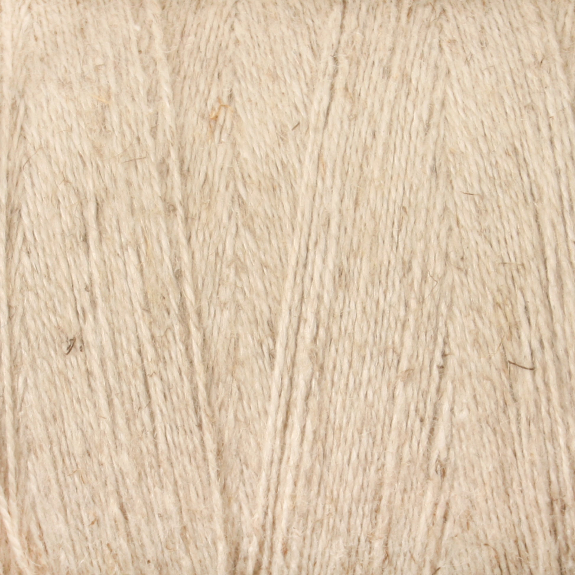 A close-up image of Maurice Brassard's 8/2 Cottolin Organic Yarn, highlighting the exquisite detail of the texture and fibers in beige. The yarn, a cotton-linen blend with a surface that showcases subtle variations in color and thickness, is reminiscent of the fibers used in a Cottolin Tea Towel Kit.