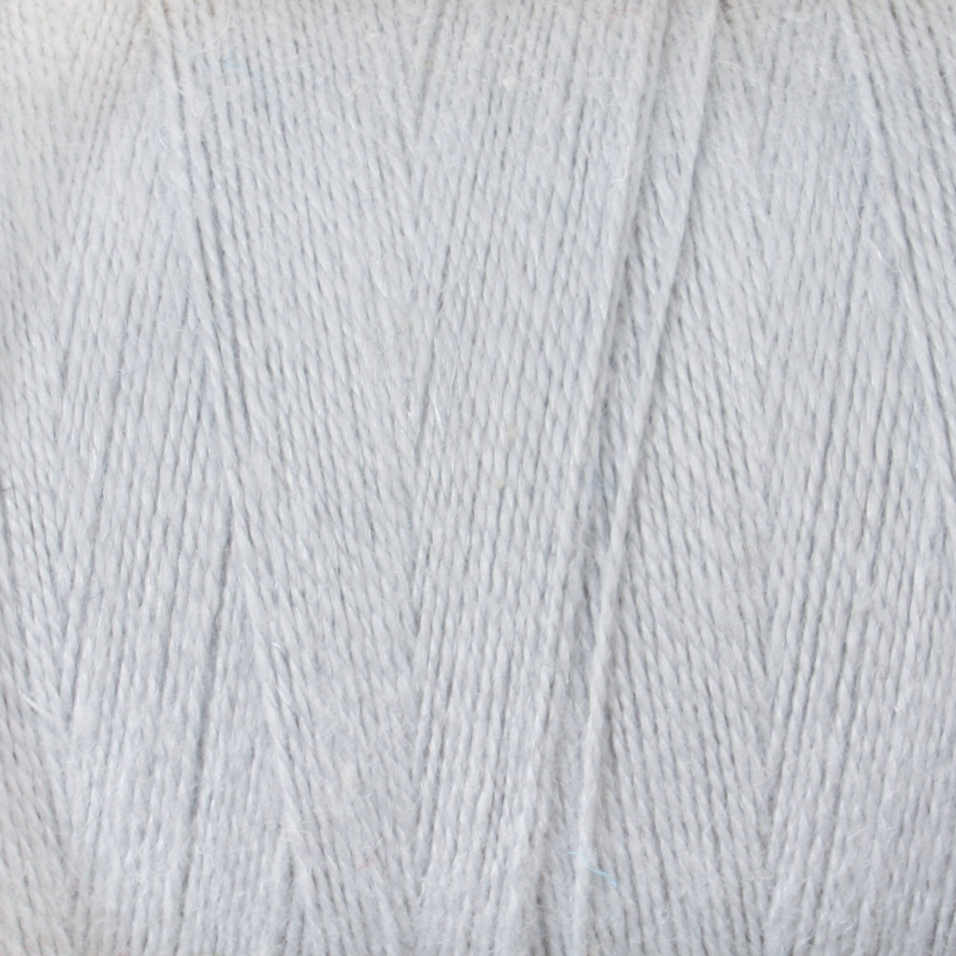 Close-up view of a large spool of light grey yarn, showing the texture and tightly wound fibers. The Maurice Brassard 8/2 Cottolin Organic Yarn | Tube highlights the soft and smooth appearance of the cotton-linen blend, perfect for knitting or crochet projects.